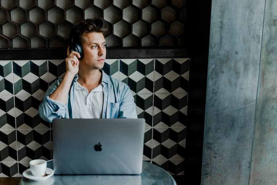Guy wearing headphones working on his laptop in a cafe. Image credit: Austin Distel.